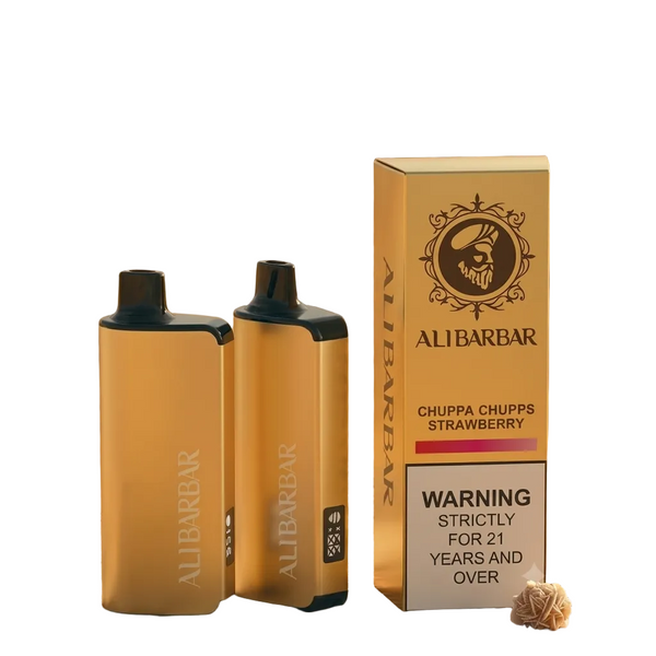 Two ALI BARBAR disposable vape devices and their packaging box on a patterned rug in a desert setting. The vapes are gold with black tops, with pinkish smoke rising from one.